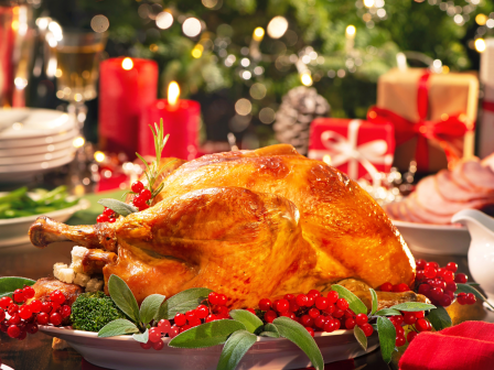 Roasted turkey and a festive table setting with red candles, berries, and warm bokeh lights.