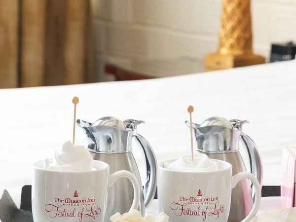 A hotel breakfast tray with mugs, a kettle, hot chocolate