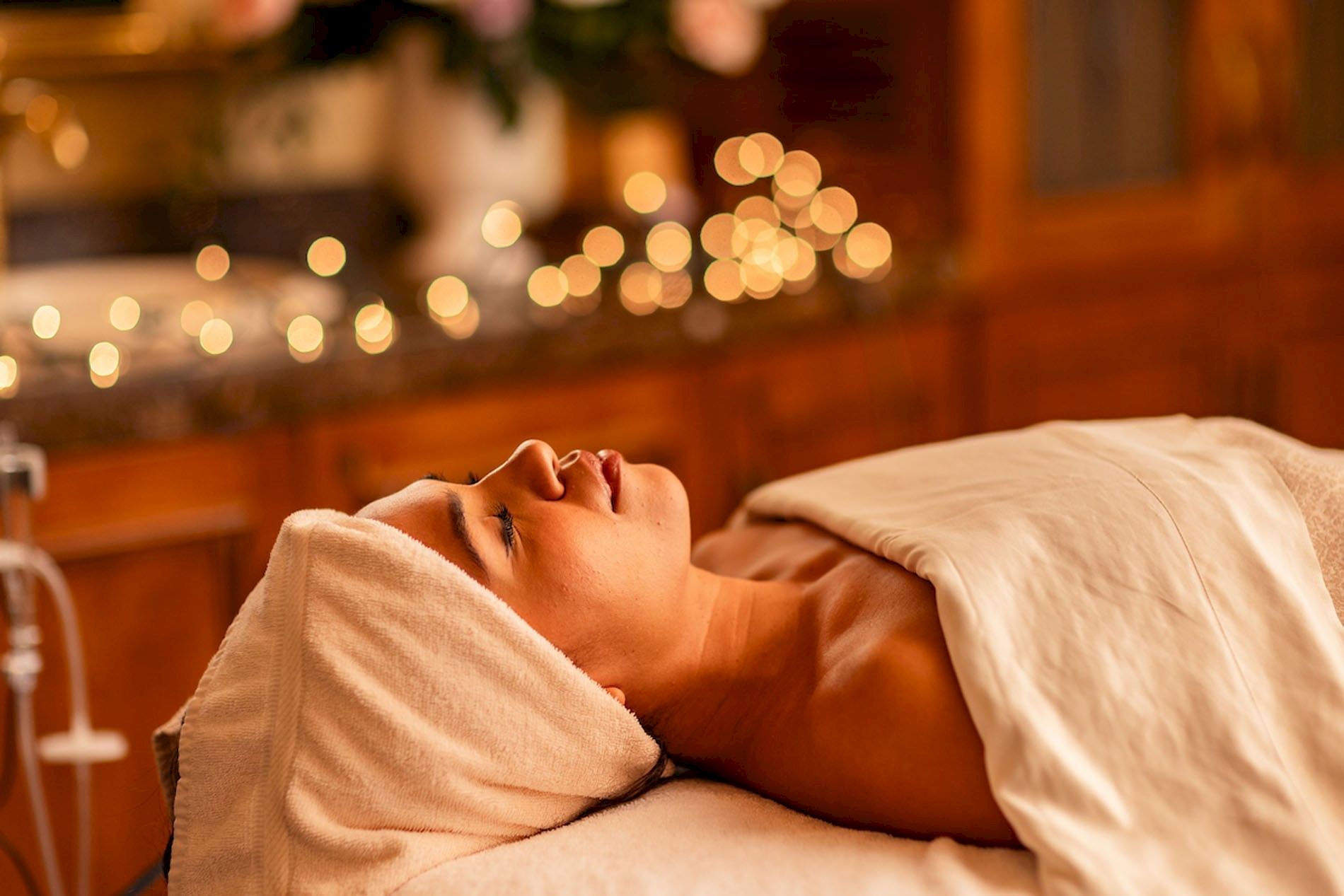 A man relaxes on a spa massage table as golden bokeh lights glow in the background.