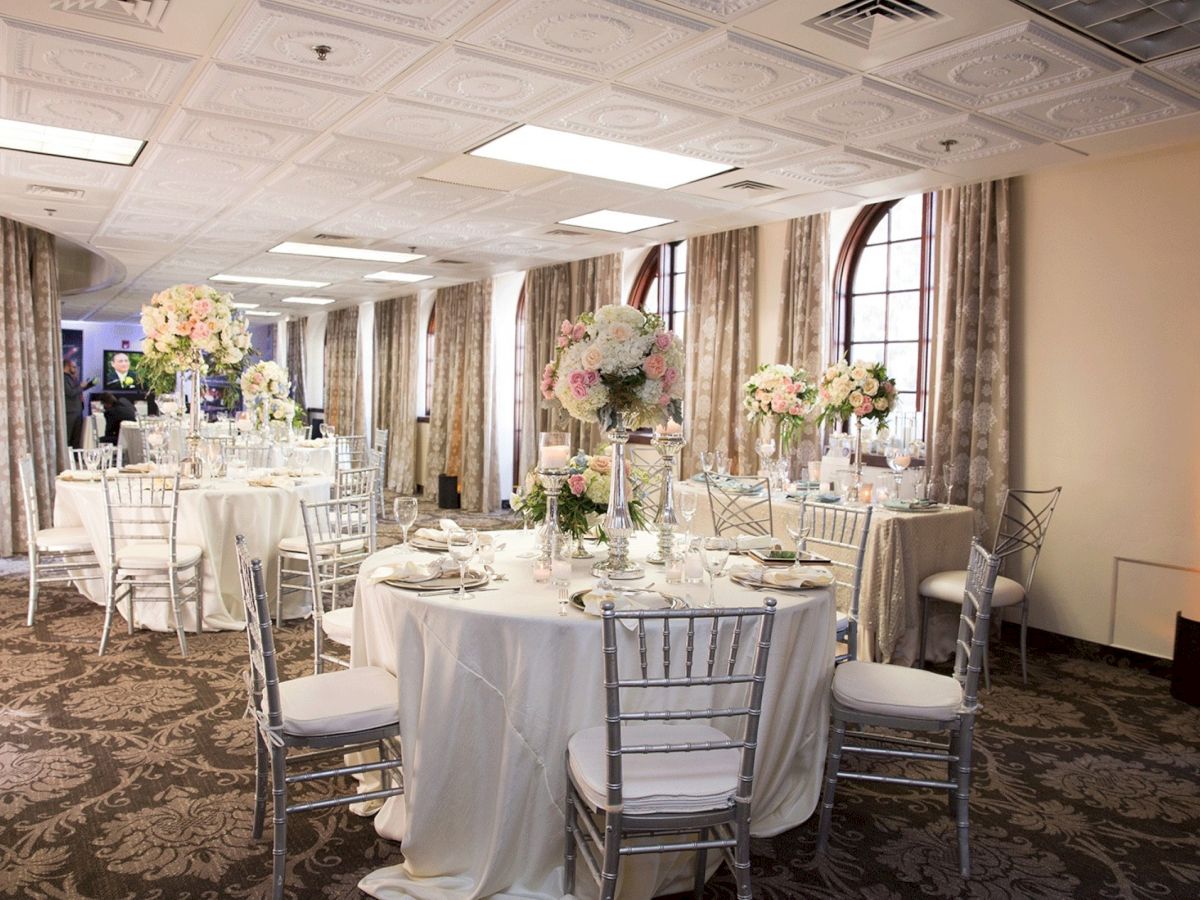 An elegant banquet hall set for a wedding, with round tables, candlelit d&eacute;cor, and large pastel floral centerpieces.