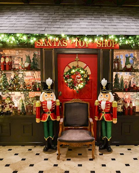 A festive &ldquo;Santa&rsquo;s Toy Shop&rdquo; window display with sparkling lights, nutcracker figures, and Christmas decorations.