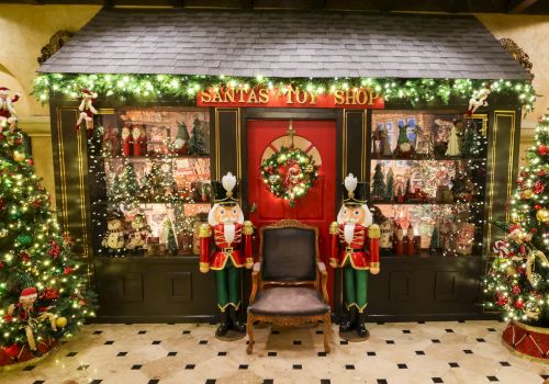 A festive &ldquo;Santa&rsquo;s Toy Shop&rdquo; window display with sparkling lights, nutcracker figures, and Christmas decorations.