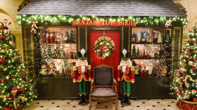 A festive &ldquo;Santa&rsquo;s Toy Shop&rdquo; window display with sparkling lights, nutcracker figures, and Christmas decorations.