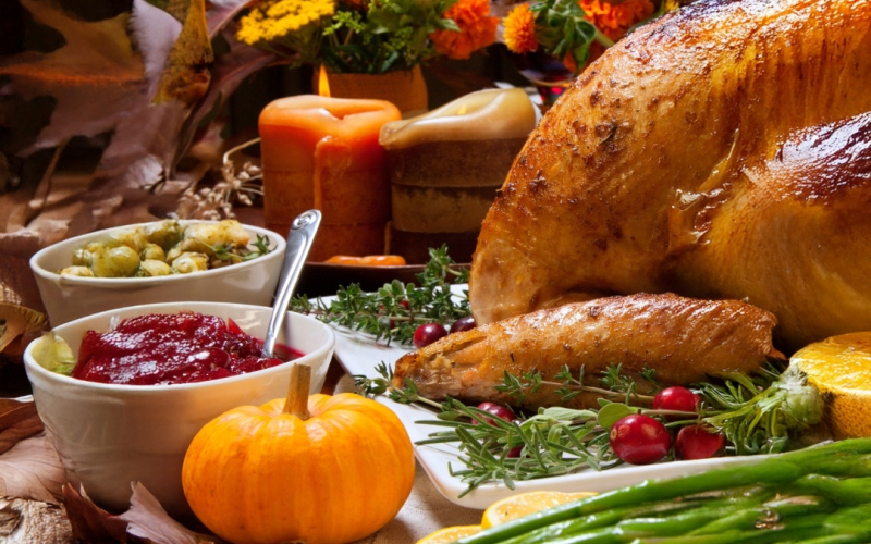 A festive holiday spread with roasted turkey, colorful sides, herbs and candles on a fall table, ready to celebrate.